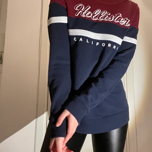 Hollister Sweatshirt Size S - Red, dark blue and white sweatshirt with the logo “Hollister California”. Very good condition. I can send the product but the buyer is paying for it.   ——   Röd, mörkblå och vit sweatshirt med logotypen "Hollister California". Mycket bra tillstånd. Jag kan skicka produkten men köparen betalar för det