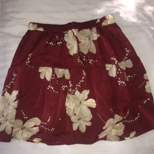 Blommig kjol - Helt ny blommig kjol, vinröd med beiga blommor på. Storlek M, passar S. Aldrig använd🥰