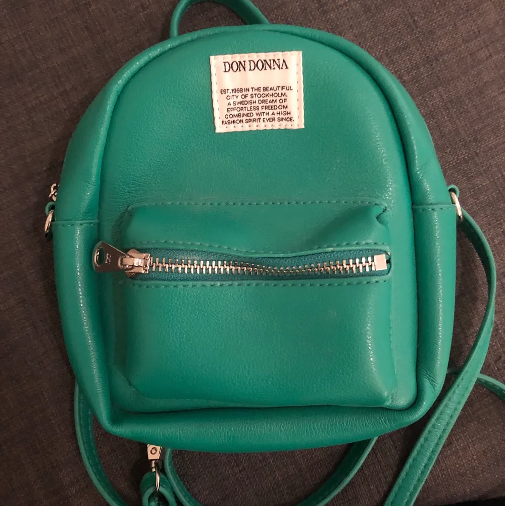 En grön aktig mini ryggsäck från DON DONNA, skriv för att få se passform, använd kanske 5 gånger, inget fel på den försöker bara rensa garderoben lite haha. Orginalpris va 800kr, säljer den för 400kr + frakt💕. Väskor.