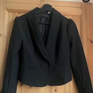 svart kavaj - Denna kavaj har använts en två gånger men är förövrigt i väldigt gott skick. Kavajen har en knapp längst ner vid magen samt detaljer som fake fickorna.  Längst upp vid armarna är tyget lite upp puffat och överlag är det enligt mig en väldigt fin kavaj.🤍 