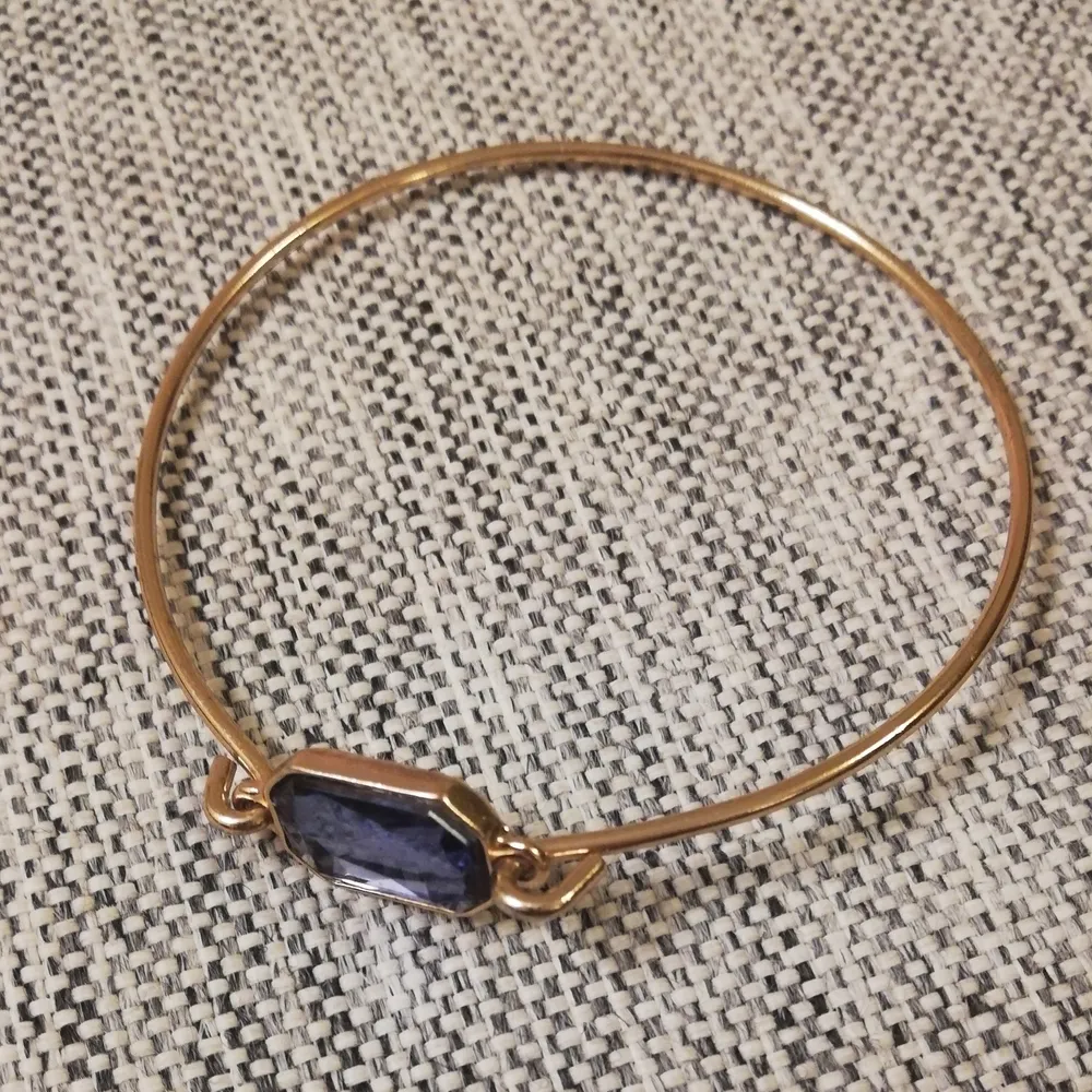 Guldigt armband med en mörkblå sten i. 29 kr, 50 kr för leverans. . Accessoarer.