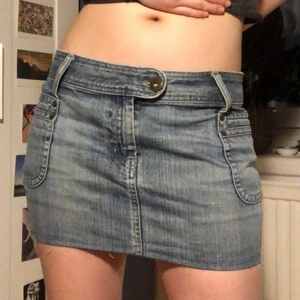 Lågmidjad jeanskjol - Ljusblå lågmidjad jeanskjol. Insydd och omsydd på vissa ställen. Midjemått 84 cm!