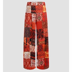 Patchy byxor - Patchy byxor från cider i röda och en del gula nyanser. De är i Strl. M och materialet är stretchigt men de är för långa i benen på mig som är 157cm. De är endast testade och lappen sitter kvar🌻