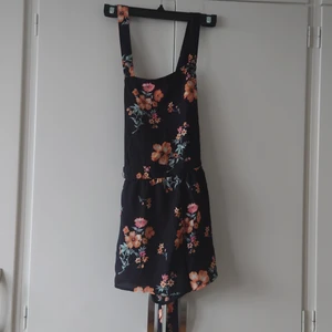 H&M hängselshorts, strl 38 - H&M svartblommiga hängselshorts med knytband i midjan. Strl 38. Endast testad. Köparen står för frakt. (Kan skickas som brev, då billigare frakt men ej spårbart) 