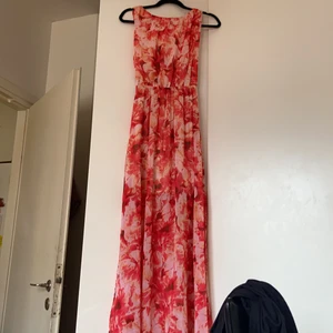 Blommig klänning  - Säljer en helt ny blommig klänning. Den har öppna slits nere vid klänning på båda sidorna, öppen där bak på ryggen. Klänning är köpt för 600 men säljs för 300 plus frakt.