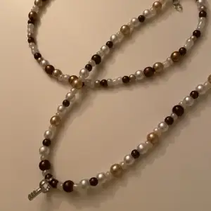 Två stycken handgjorda halsband med bruna pärlor, ett halsband med en nyckel och ett med bara pärlor. Lite större än en choker 