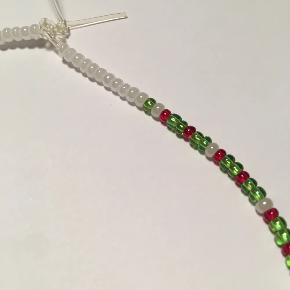 Handgjort halsband med glaspärlor i färgena vit, grön, röd och en större pärla i orange✨Kontakta om du är intresserad✨. Accessoarer.