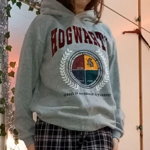 Hoodie  - Grå hoodie med ett hogwarts märke på.