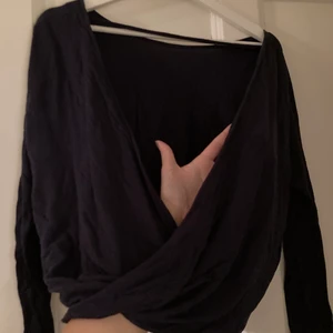 Mörkblå topp med öppen rygg - Marinblå långärmad topp med öppen rygg. Omlott längst ner. 