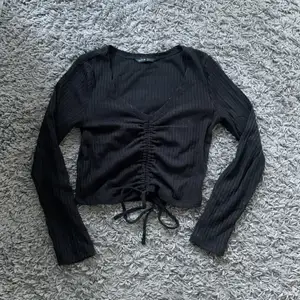 En svart ribbad tröja ifrån shein. Den har ett band som går att knyta och man kan dra så att den blir kort eller lång, Inte bästa kvaliten, men lite vad man får föreställa sig när det är från shein.