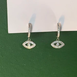 silvriga örhängen med ögon! - örhängen i stål köpta på punktshop! örhängena är små ögon med stenar på! säljer då de inte kommer till användning ✨ frakten ingår i priset. 