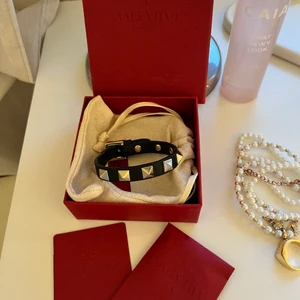 Valentino armband  - Valentino armband med guld nitar. Tyget har gått upp där justerar storleken på bandet men ingenting som syns när man bär armbandet samt att jag fixar det så gott det går innan jag postar. Allt på bilden följs med.  Ingen budgivning! Först till kvarn därav fast pris!