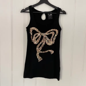 Svart längre linne med guldpaljetter - Säljer ett svart lite längre linne med paljetter från Cubus. Strl S. Knappt använd. Snygg passform