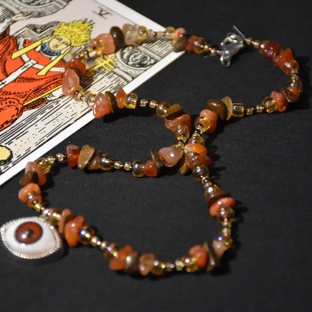 Halsband med olika glaspärlor, äkta karneol och bronsit samt en ögonberlock. . . Accessoarer.