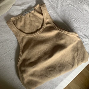 Topp  - Säljer ett beiget ribbat linne från NAKD, super trendigt nu till vår och sommar🥰