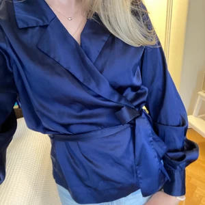 Sidenblus blå  - Mörkblå fin sidenblus från Bikbok strl S. Man knyter i midjan passar därför fler strl. En defekt och det är att en knapp på en av handlederna är borta men det är inget som märks om man inte letar det medvetet (insidan armen dessutom). 