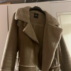 Zara jacka - Väldigt fin brun/beige pilotjacka med Teddy fleece inuti från Zara. Jackan har använts men är fof mycket fin, inga skador eller slitningar. Den är i en storlek XL. Säljer för att den inte längre är min stil och inte kommer till användning. Köparen står för frakten :)