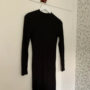 Svart klänning med liten polokrage - Svart, tajt, knälång klänning med polokrage och långa ärmar. Elastiskt och mjukt material.   Hämtas på plats eller skickas med post. Vill du ha den skickad tillkommer fraktkostnad på 45 kr (priset för postnords blå påse).