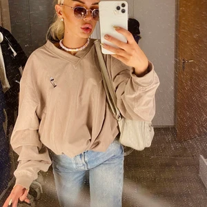 Varm tröja/jacka i windbreaker material - Beige-brun tröja i strl S men oversize så jag uppskattsr till en M.  Det är windbreaker-aktigt material på insidan som gör den varm så som en vårjacka är. Nyskick! Insidan är mjuk och skön ☺️