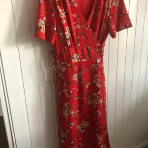 Ny rödblommig klänning från vero Moda i storlek S. Omlott med snörning i midjan. Vadlånga 