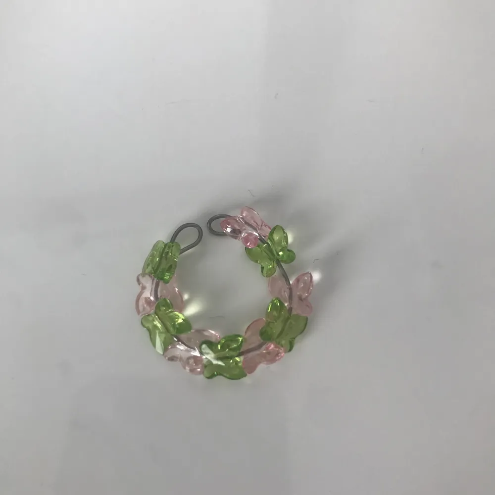 Ring gjort av ståltråd och har rosa o gröna fjärilar🌸🌿 Ringen är öppen och då justerbar så den passar alla fingrar!. Övrigt.