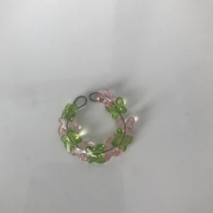 Egengjord ring  - Ring gjort av ståltråd och har rosa o gröna fjärilar🌸🌿 Ringen är öppen och då justerbar så den passar alla fingrar!