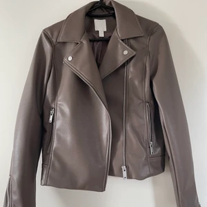 Brun skinnjacka - Brun skinnjacka från HM. Storlek 34. Supersnygg brun färg!! Bilden gör färgen inte riktigt rättvisa. Buda i kommentarerna. Utgångspris: 50kr.