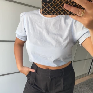 En somrig blus - En somrig ljusblå blus med fina resår detaljer i ärmarna. Den är sparsamt använd och är i storlek 38 (den är ganska liten i storleken) 