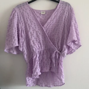 Ljuslila omlottblus - Storlek 38, från Jacqueline de yong. Passar S/M beroende på hur man vill att den skal sitta. Använd en kväll, tyvärr för stor för mig. Går att spänna med knytband i midjan 