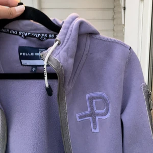 Pelle P tjocktröja - Ljuslila tjocktröja från Pelle P. 2 fickor utan dragkedja och en ficka på armen med dragkedja. Bra kvalitet och perfekt att ha på sommarkvällar. Skickas imon Sverige.