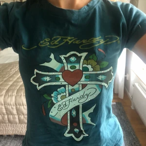 ED HARDY baby tee - Sjukt söt baby-tee från Ed Hardy. Väldigt y2k och jätte fina ”rhinestone”- detaljer på trycket. Köpt second hand och därefter sparsamt använd, i mycket bra skick. Strl M men tror det är barnstorlek, passar på mig som har xs men passar nog xxs-m