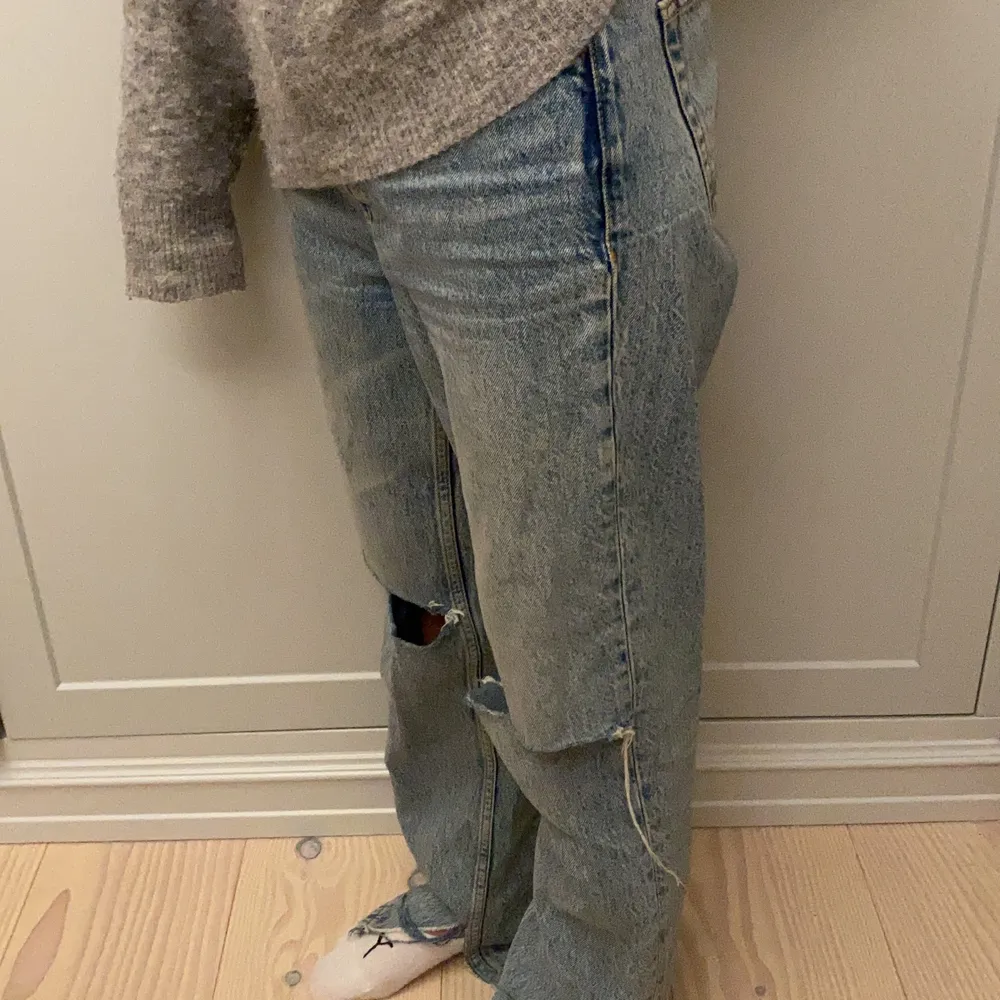 Supersnygga jeans med hål vid knäna samt slits. Jeansen lägger sig fint över skor och kan bäras på höfterna. Passar någon runt 160- 170 cm. Bra skick! . Jeans & Byxor.