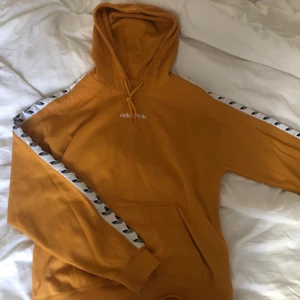 Gul Adidas Hoodie - En gul adidas Hoodie som är knappt använd. Fick den i present för ca ett år sen. Inga fläckar eller fel som jag kan se. Är i strl S men funkar som M, och den passar både killar och tjejer! FRAKTEN BETALAR KÖPAREN!
