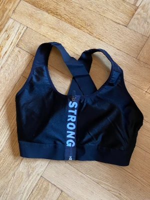 Sport BH/Topp - Svart Sport BH/topp med korsad rygg. Använd endast en gång och därefter tvättad.