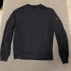 Belstaff tröja - Säljer denna Belstaff crewneck då den tyvärr har blivit förliten. Okej skick, litet hål vid handleden (märks knappt).                                                            Nypris: 1500kr