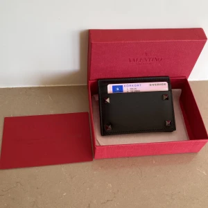 Valentino korthållare  - Säljer en äkta valentino korthållare. Den är i nyskick och är knappt använd med alla spikar kvar. Nypris 3000kr säljer den för 999