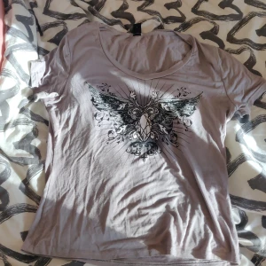 Grå t-shirt - Grå t-shirt med print på. Säljer den då jag trodde den skulle vara större. Den är stretchig. Den är i storlek L men känns mer som en M. 