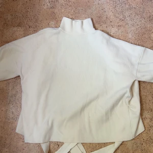 Stickad tröja med öppen rygg - Vit stickad tröja i storlek XS från Nelly. Otroligt fint material och kan knytas bak i ryggen. 