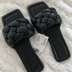 SANDALER SVARTA 38 - Säljer dessa snygga svarta flätade sandalerna som är helt oanvända prislapp kvar på, inköpta förra året. Storlek 38. Normal i sin storlek. Säljer för 120 kr. Köparen står för frakten!