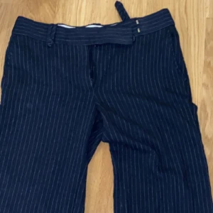 Lågmidjade kostymbyxor  - Dessa är mina favorita kostymbyxor, jag älskar de men tyvärr har de blivit lite försmå. Har aldrig haft ett par byxor som sitter så här snyggt, de är mörkblåa med ränder och sånt spänne. Kontakta mig om ni frågor eller vill ha fler bilder, mått osv!