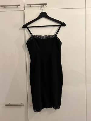 Svart klänning m spetskant  - Svart kort klänning m spetskant och öppning i ryggen. Använd 1 gång 