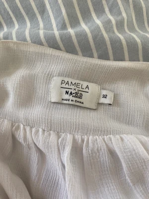 Vit volang topp  - Vit volang topp från NA-KD x PAMELA i strlk  32, säljer då den är för liten, sparsamt använd och inga defekter 