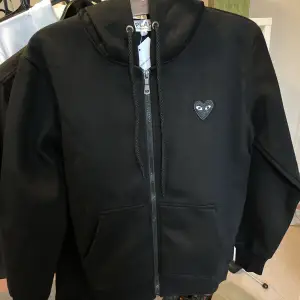 En svart helt ny och oanvänd hoodie från CDG. Denna tröja passar till ALLT och har dessutom en otroligt mjuk och  bekväm insida samt en smidig dragkedja. Vid intresse eller övriga frågor är det bara att höra av sig! Mvh❣️🤝🙏 Insta: @Designerdripplug