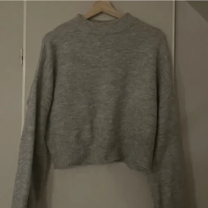 Stickad tröja - Ljusgrå stickad tröja från NA-KD, använd fåtal gånger. Lite högre krage och vida armar längst ner, superfin! Kommer tyvärr inte till anledning därför jag säljer. 