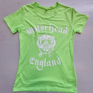 Motörhead Dam t-shirt med hårdtock - Neongrön t-shirt med vitt Motörhead tryck fram *Armhåla till Armhåla ca. 40 cm. * Tot. längd ca. 60 cm.