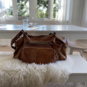 Stor snygg och praktisk vintage kameraväska i skinn/läder - Snygg, stor och praktisk vintage kameraväska i vackert cognac färgat skinn/läder. Retro. Snyggt bruksslitage. Ca 55 cm bred, höjd ca 30 cm, djup ca 28 cm.