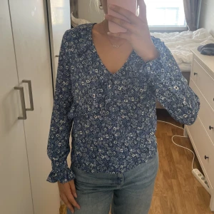 Blommig blus  - Jättesöt blå, blommig blus med lite puffiga ärmar. 