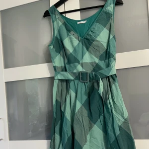 Grön klänning - Grön vintage klänning i mycket fint skick!  Längd: mellan knä och mitten av låren på mig som är 175.  Bält är avtagbart. Dragkedja på sidan av klänningen.  