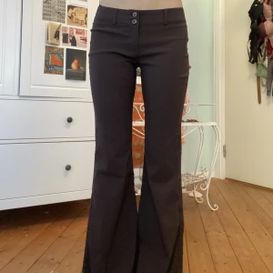 Lågmidjade utsvängda kostymbyxor - Så fina utsvängda kostymbyxor, mörkbruna och lågmidjade. Jag har klippt av dem själv då de var för långa för mig så de är lite trådiga längst ner. Midjemått: 35cm (tvärs över), innerbenslängd: 75cm. Sitter så snyggt och bekvämt!