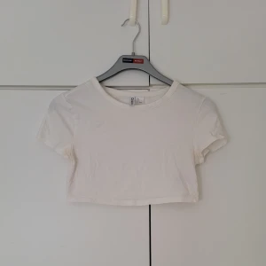 Vit tshirt - Vit croppad tshirt från H&M i storlek M. Har små fläckar vid armhålorna (se bild). Är ca. 26 cm lång. 